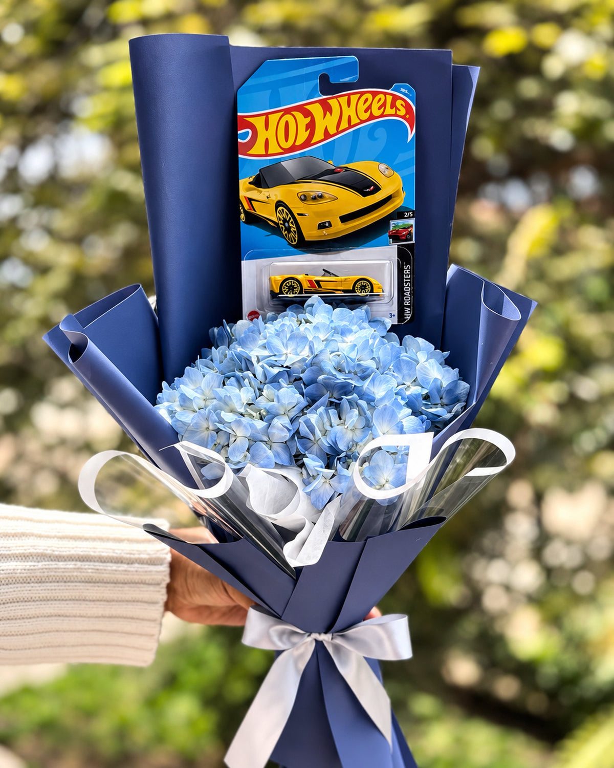 Ramo de flores azules con Hot Wheels en envoltura azul y lazo plateado - Florería Bloom Lima